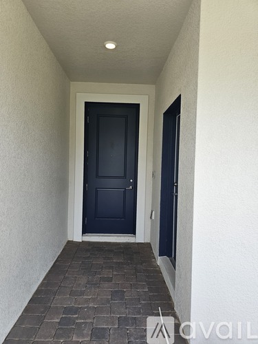 A hallway with a black door and a brick floor.