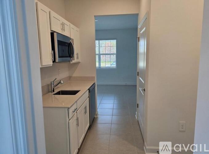 A kitchen with white cabinets and a microwave above the sink.