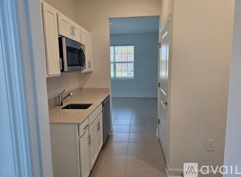 A kitchen with white cabinets and a microwave above the sink.