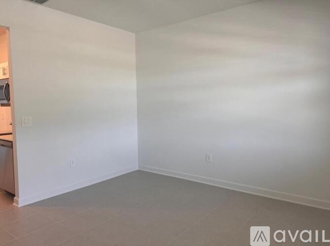 A spacious room with white walls and a ceiling fan.