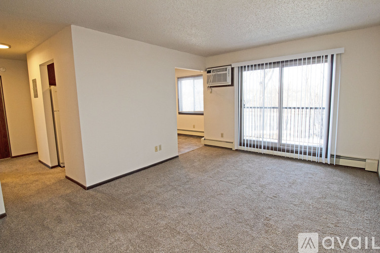 A sparsely furnished living room with a window and sliding glass door.