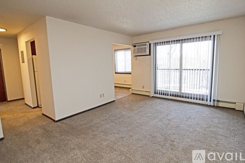 A sparsely furnished living room with a window and sliding glass door.