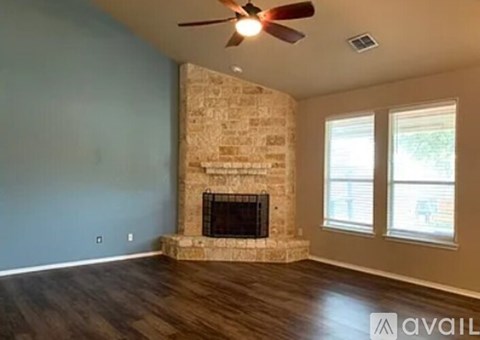 A living room with a stone fireplace and a ceiling fan.