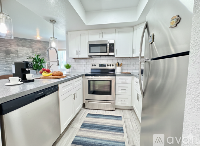 A spacious room with wooden flooring and a kitchen area in the background.