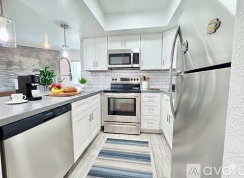A spacious room with wooden flooring and a kitchen area in the background.