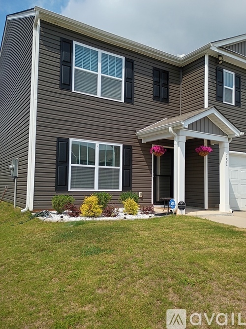 A two-story house with a front porch and a small garden.