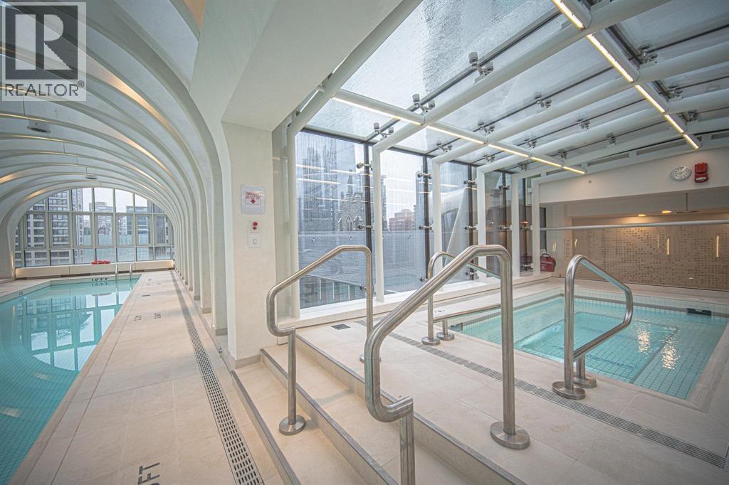 A large indoor pool with a glass ceiling and a metal railing.