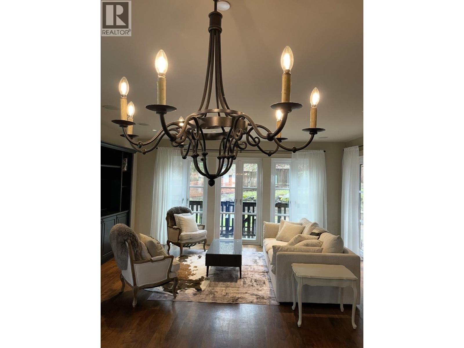 A chandelier hangs over a white couch in a well-lit room.