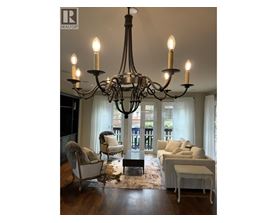 A chandelier hangs over a white couch in a well-lit room.