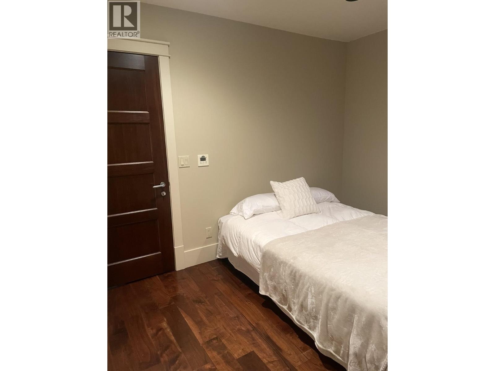 A bedroom with a bed, pillow, and a door.