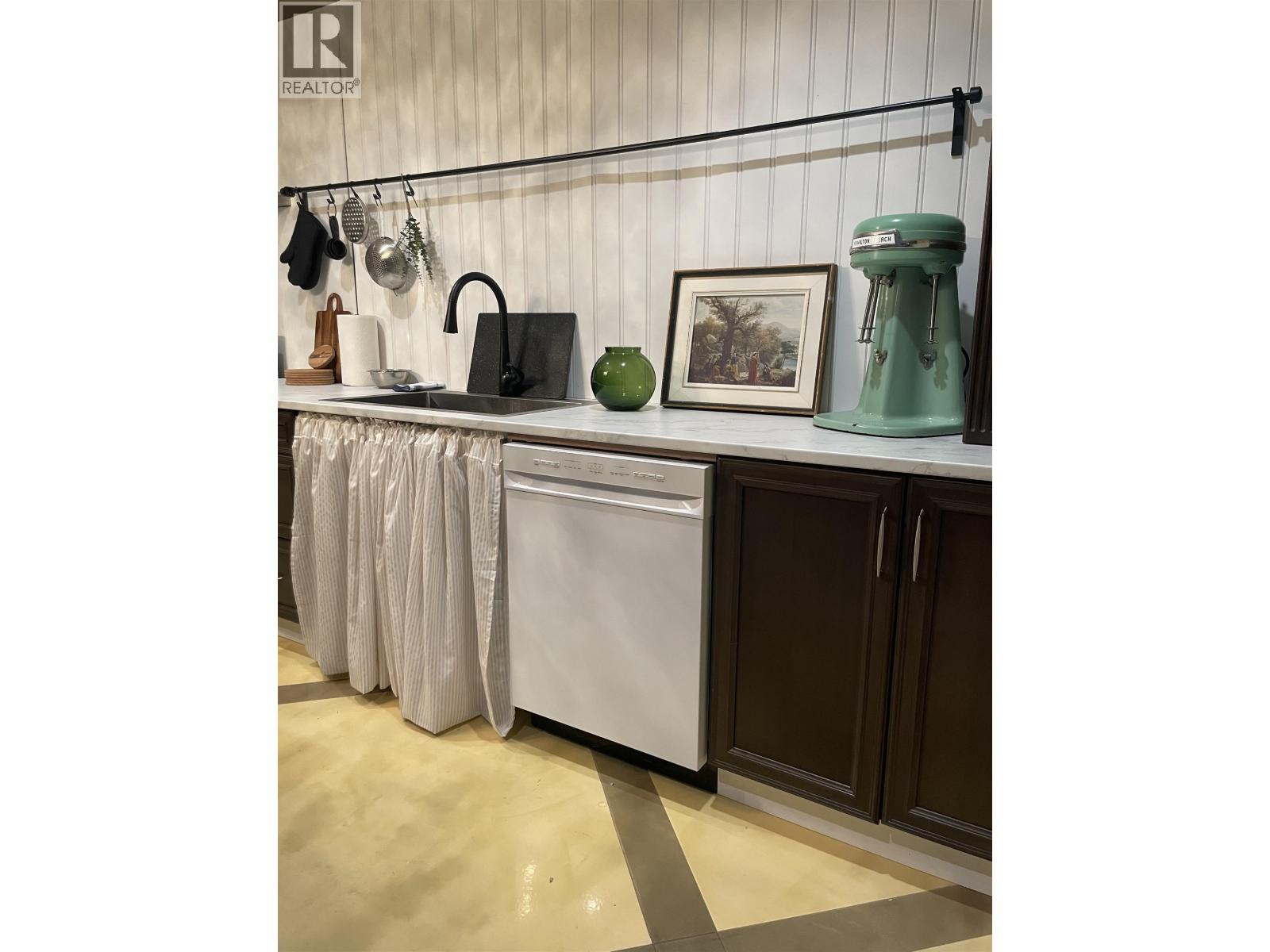 A kitchen with a white dishwasher and a green kettle.