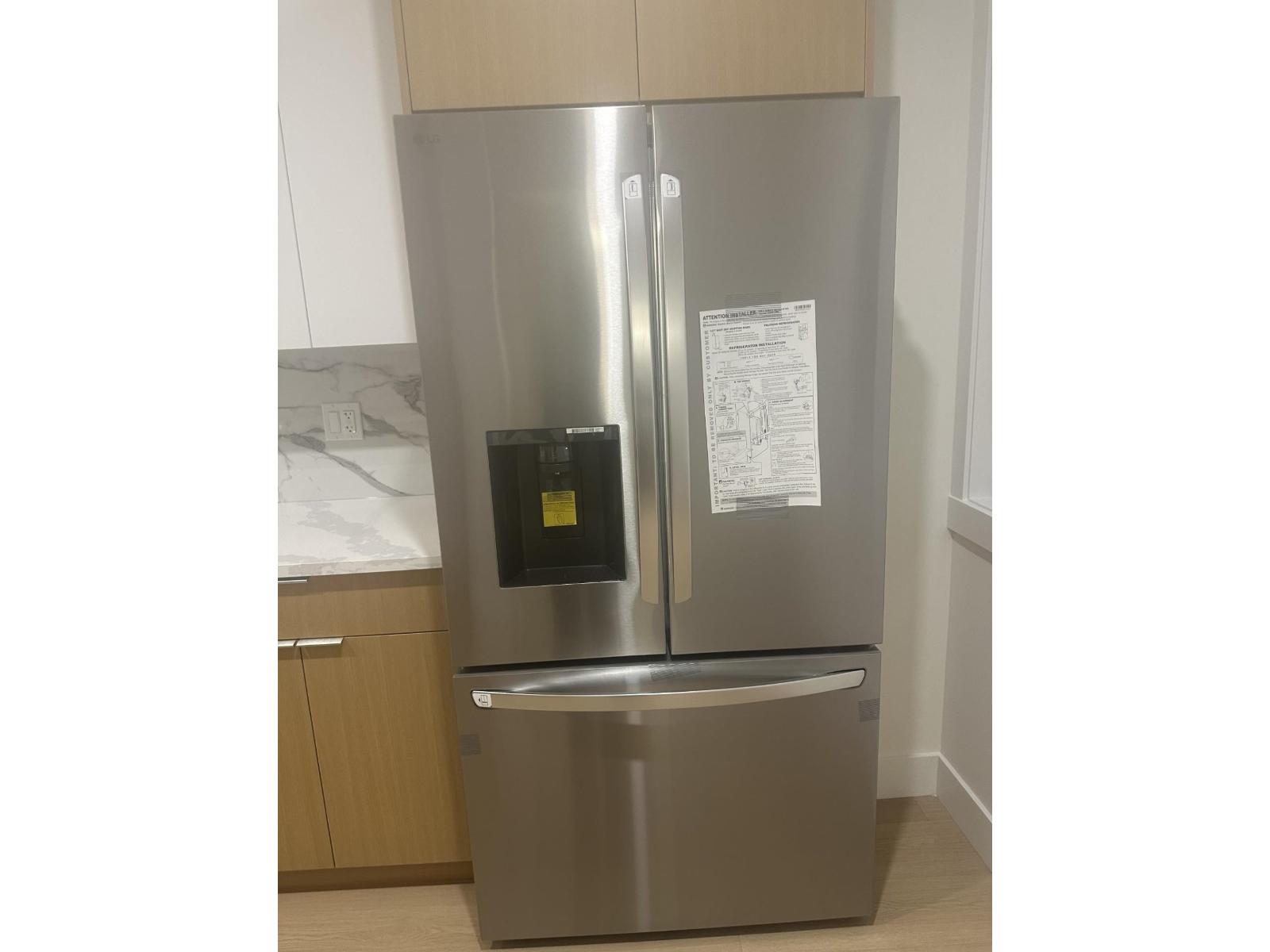 A stainless steel refrigerator with a black water dispenser on the left side and a paper on the right side.