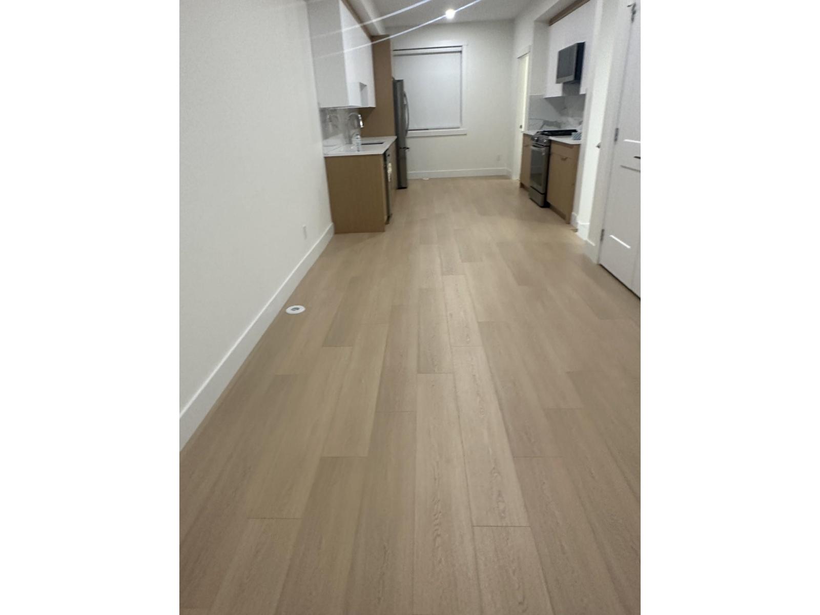 A long hallway with wood floors and white walls.