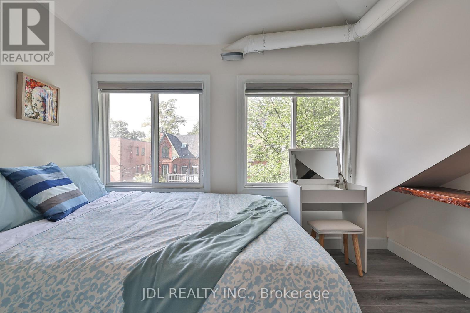 A bedroom with a bed, desk, and window.