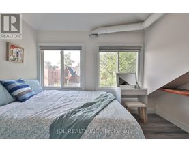 A bedroom with a bed, desk, and window.
