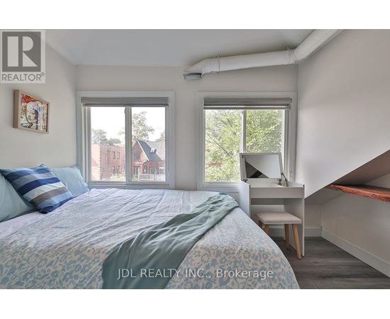 A bedroom with a bed, desk, and window.