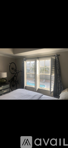 A bedroom with a large bed and a view of a pool through the window.