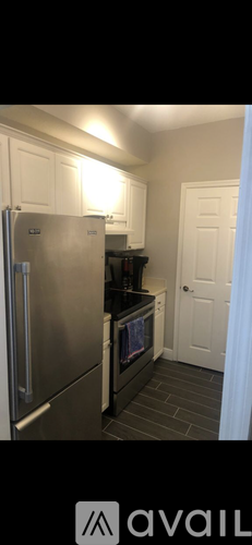 A kitchen with a stainless steel refrigerator and black countertops.