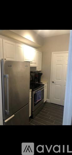 A kitchen with a stainless steel refrigerator and black countertops.