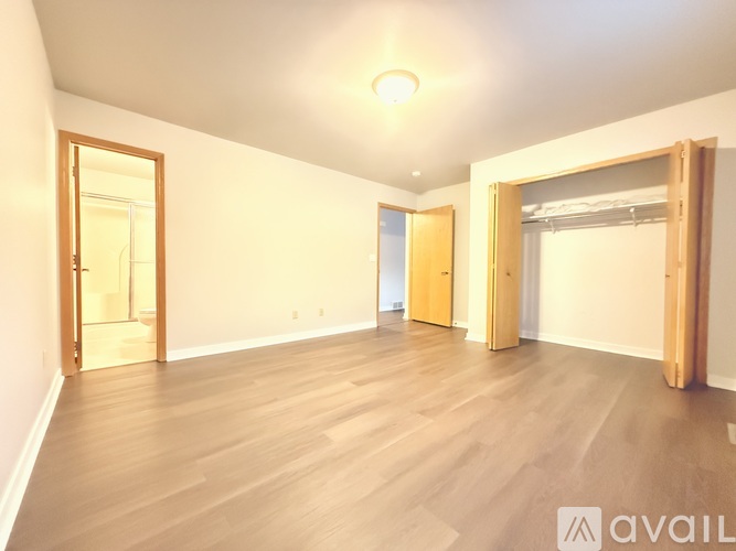 A spacious room with wooden floors and two open doors.