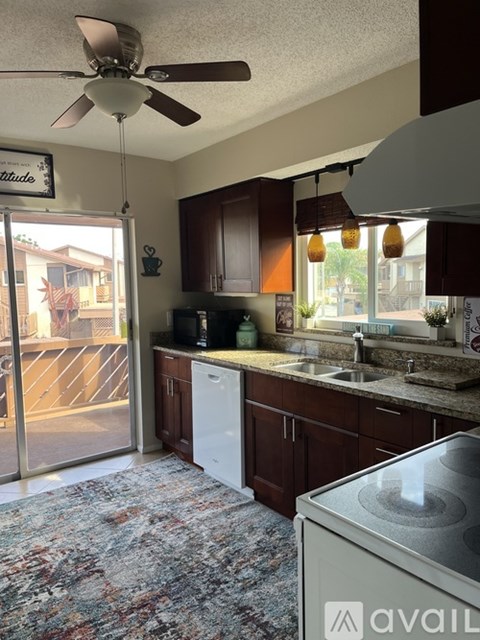 A kitchen with a white dishwasher and a fan on the ceiling.