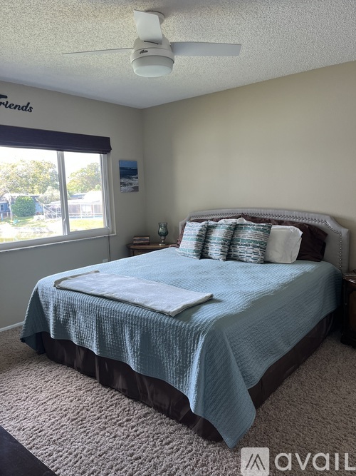 A bedroom with a bed, pillows, and a ceiling fan.
