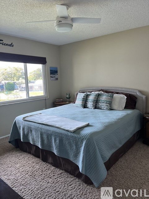 A bedroom with a bed, pillows, and a ceiling fan.