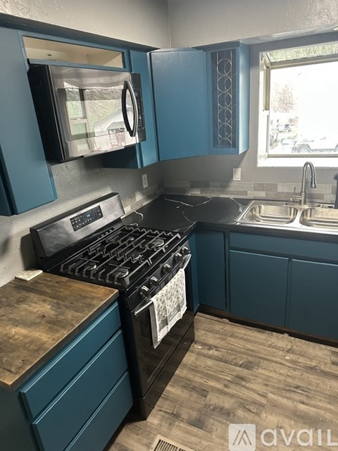 A kitchen with a black stove top oven and blue cabinets.