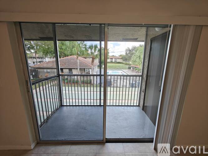 A balcony with a metal railing and glass doors leading to a pool area.