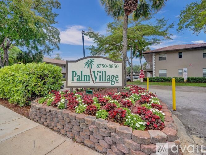 A sign for Palm Village stands in front of a building with a phone number on it.