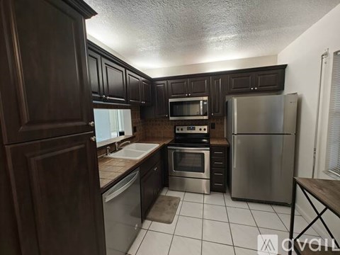 A kitchen with dark wood cabinets and stainless steel appliances.
