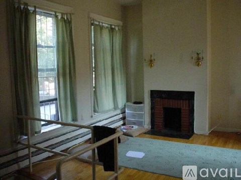 A living room with a fireplace and a window with green curtains.