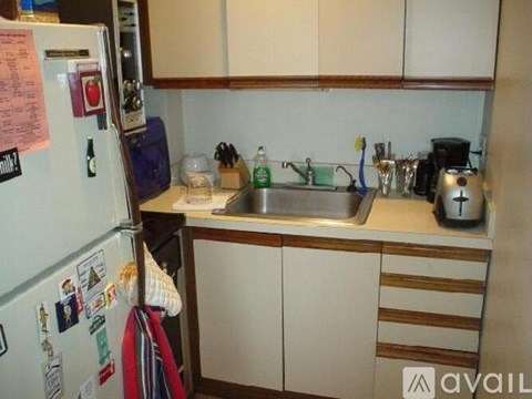 A kitchen with a refrigerator covered in magnets and a sink with a faucet.