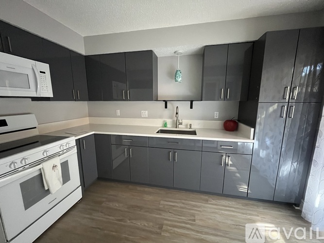 A kitchen with a white stove and black cabinets.