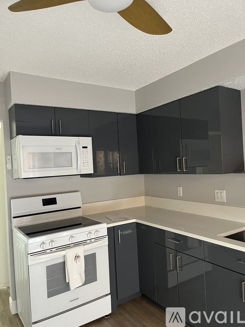 A kitchen with a white stove and black cabinets.