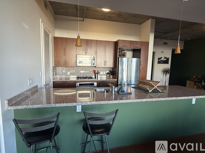 A kitchen with a granite countertop and two black chairs.