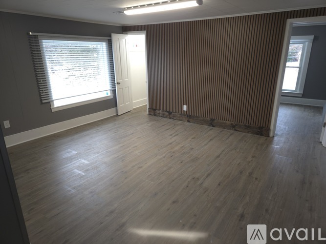 A room with wooden flooring and a window with blinds.