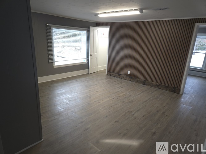 A room with wooden flooring and a window with blinds.