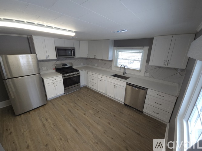 A kitchen with white cabinets and a wooden floor.