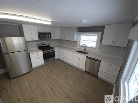 A kitchen with white cabinets and a wooden floor.