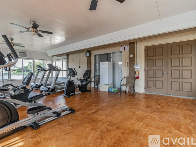 A gym with treadmills, exercise bikes, and a ceiling fan.