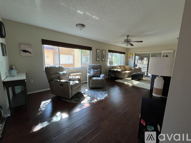 A living room with a ceiling fan and a rug on the floor.
