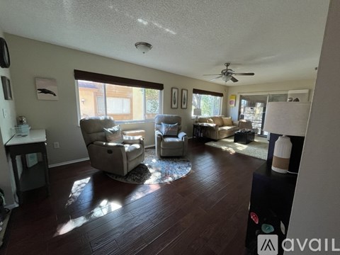 A living room with a ceiling fan and a rug on the floor.