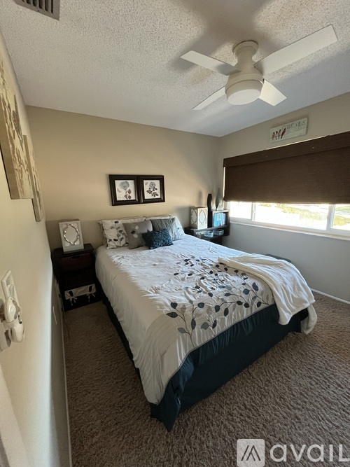 A bedroom with a bed, nightstands, and a ceiling fan.