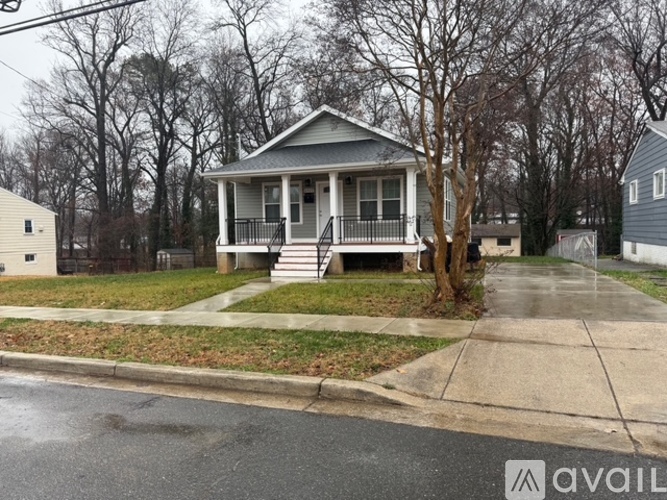 A house with a porch and a tree in front of it.