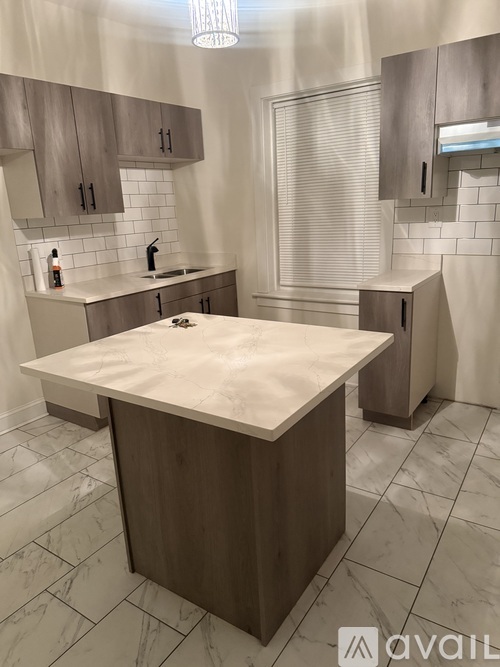 A kitchen with a marble countertop and wooden cabinets.