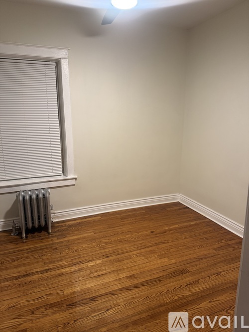 A room with wooden flooring and a window with blinds.