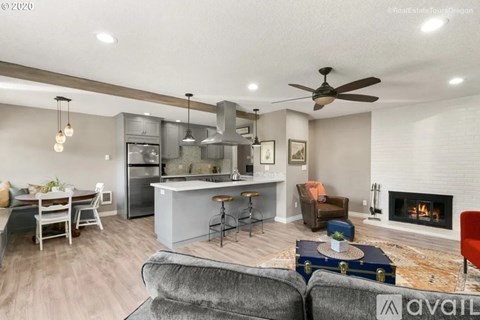 A modern living room with a fireplace and a kitchen area in the background.
