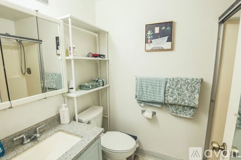 A bathroom with a toilet, sink, and a picture on the wall.
