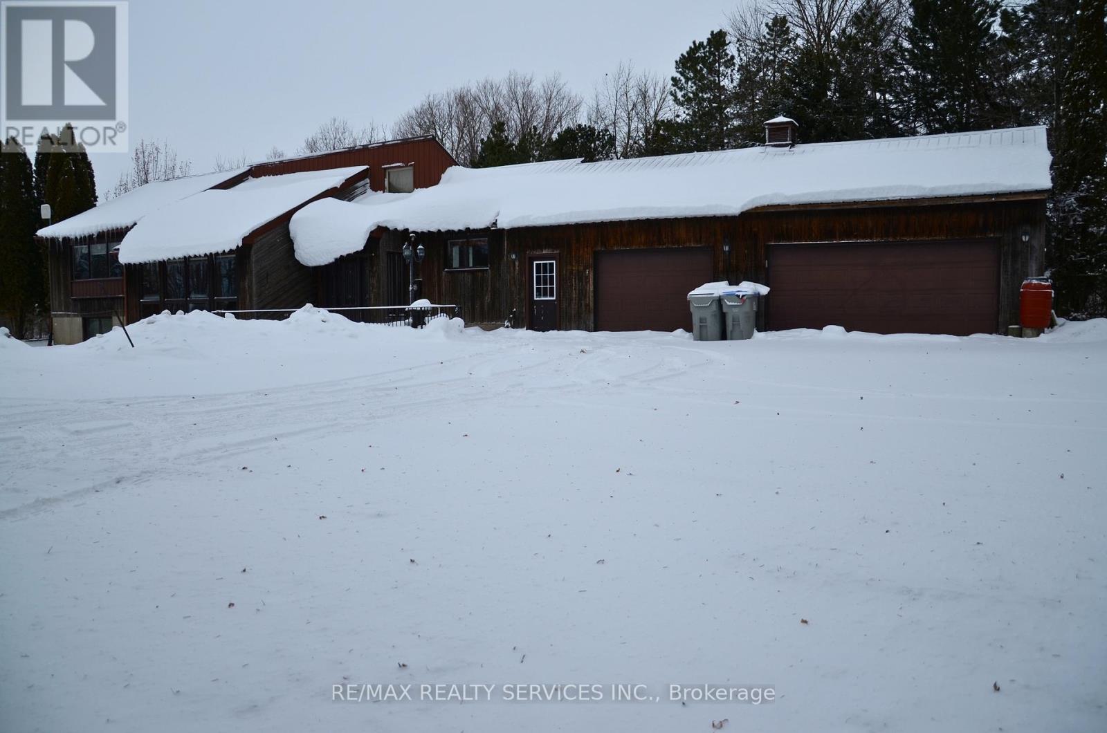 A snow-covered house with a red garage door.
